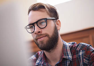 Jeune homme adulte portant des lunettes de vue Lissac devant un ordinateur